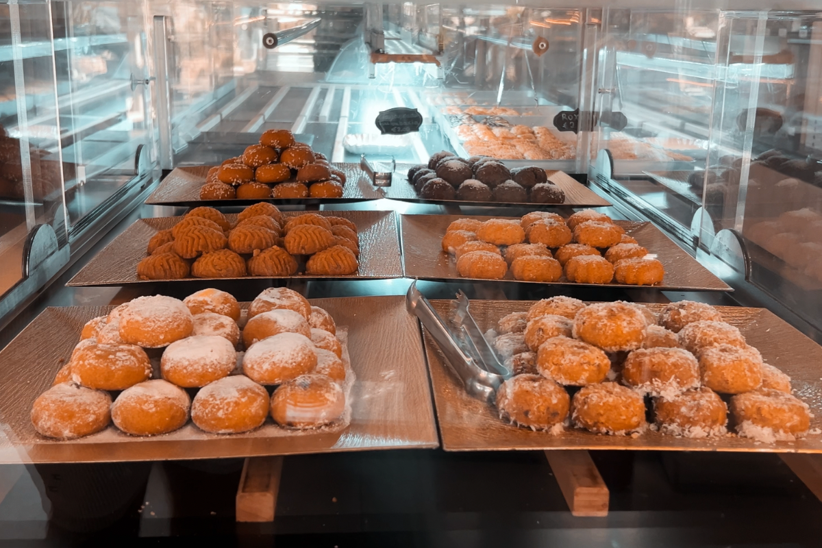 StoArtos bakery display case with trays of plant-based Cypriot pastries dusted with coconut and sesame